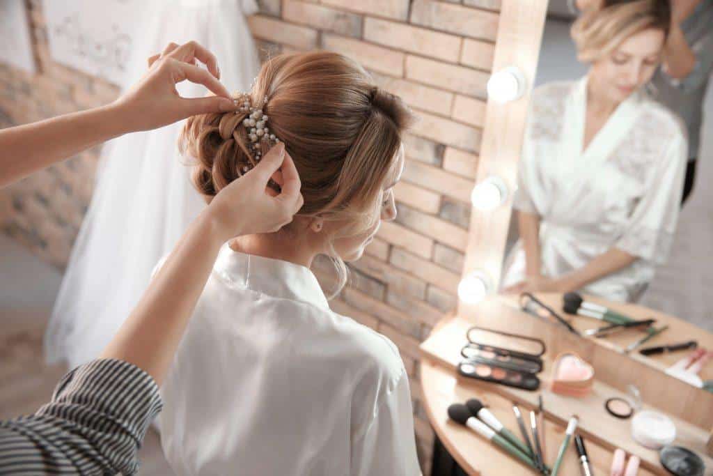 Hairdresser preparing bride before her wedding in room alt=""