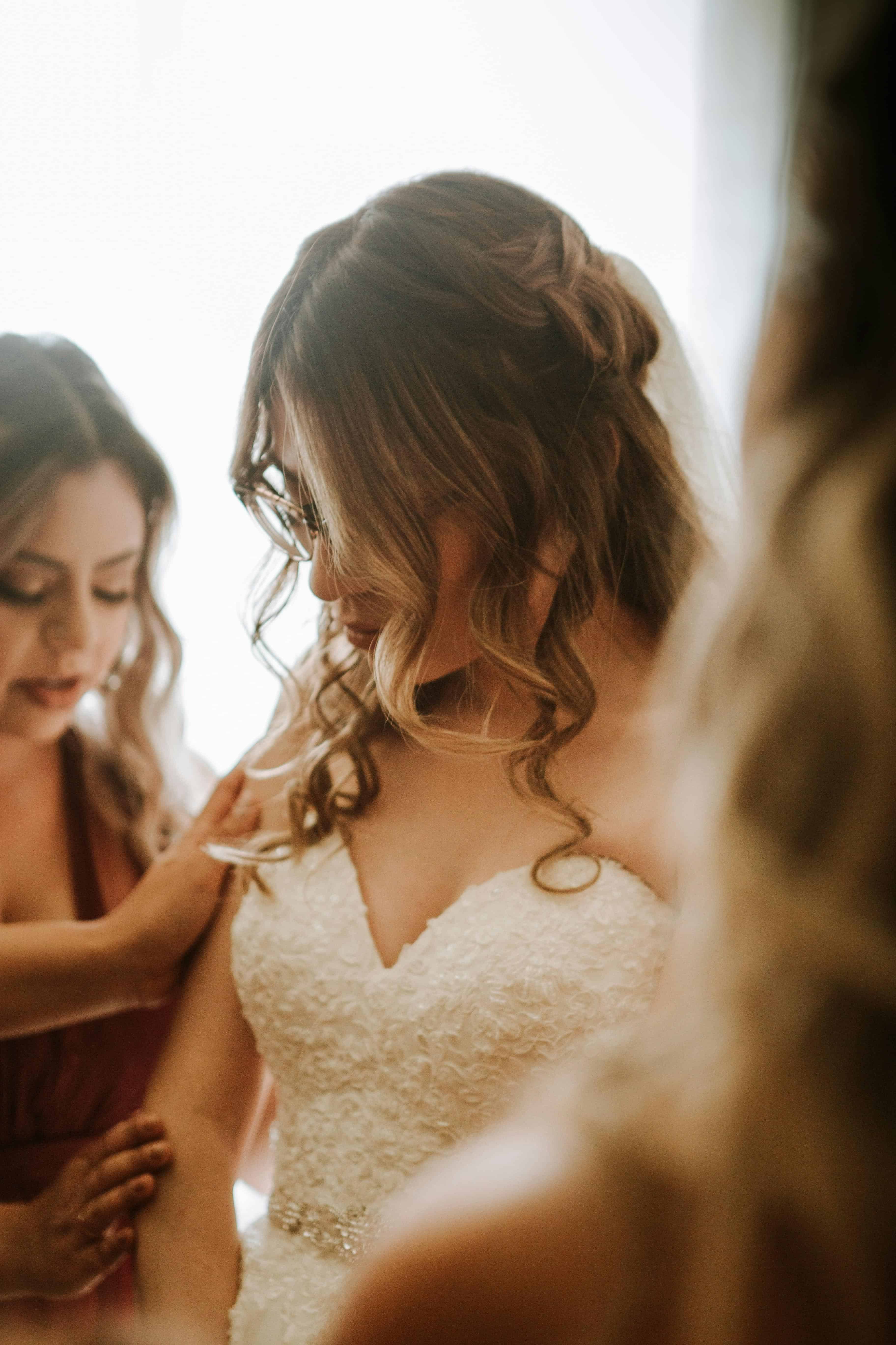 soft-waves-bridal-hair-wedding-day-style.jpg Bride being helped by her bridesmaids during wedding morning preparations.